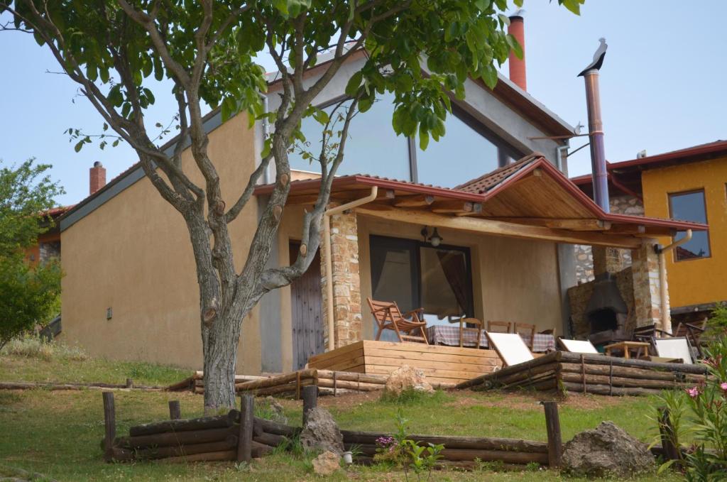 une maison avec une terrasse couverte dotée de chaises et d'un arbre dans l'établissement DIMITRA's VILLAS, à Elatochori