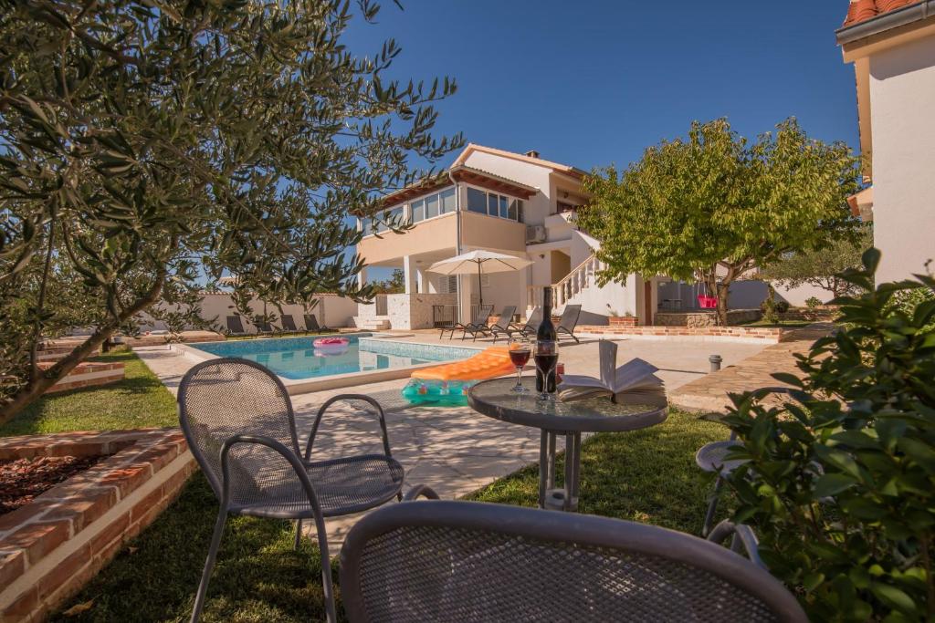 een achtertuin met een tafel en stoelen en een zwembad bij Holiday home Dinko in Pridraga