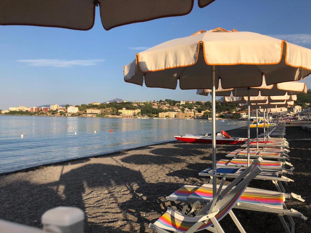 een rij stoelen en parasols op een strand bij Hotel Tirreno in Sapri