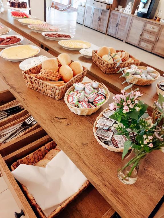 Breakfast buffet display with baskets of rolls, packaged spreads, sliced cheeses and cutlery.
