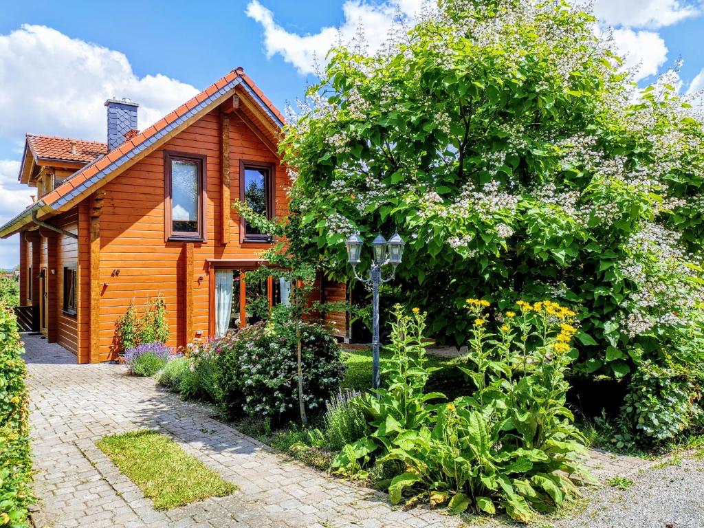 una casa de madera con un árbol delante en Gemütliches Blockhaus am Wald mit großem Garten, en Waltershausen