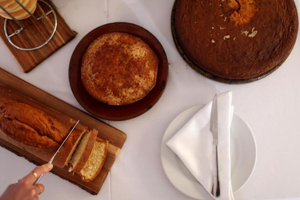 a table with cakes and plates and a person holding a knife at Hotel Punta Sur in Tarifa