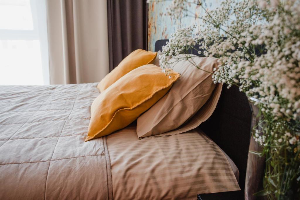 科沙林的住宿－W&K Apartments - Ginger Suite，床上有枕头,花瓶上放着鲜花