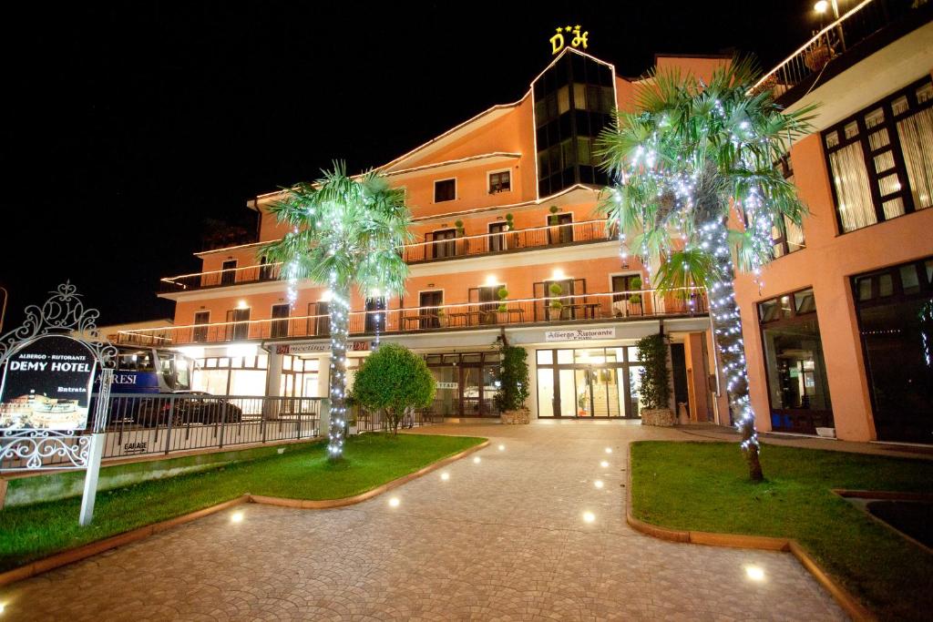 a building with two palm trees in front of it at Demy Hotel in Aulla