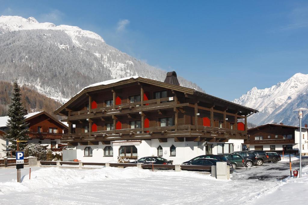 a large building with cars parked in the snow at Hotel Garni Maria Theresia in Sölden