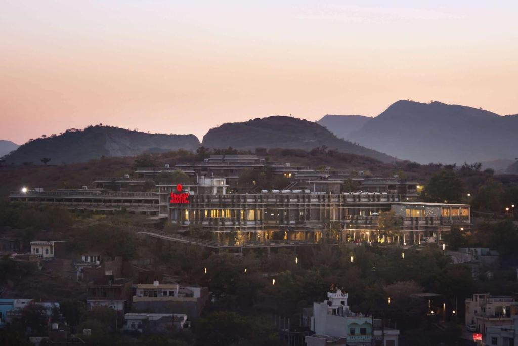 a view of a building with mountains in the background at Ramada Udaipur Resort & Spa in Udaipur