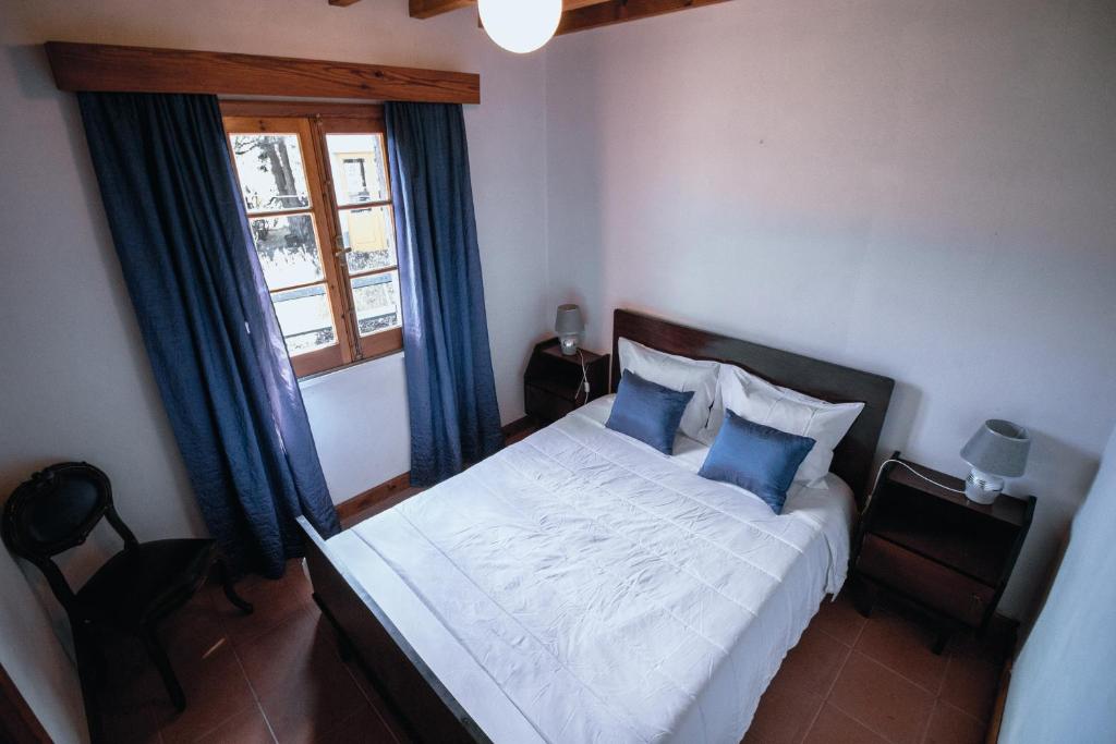 una camera da letto con un letto con cuscini blu e una finestra di Sete Cidades House a Sete Cidades