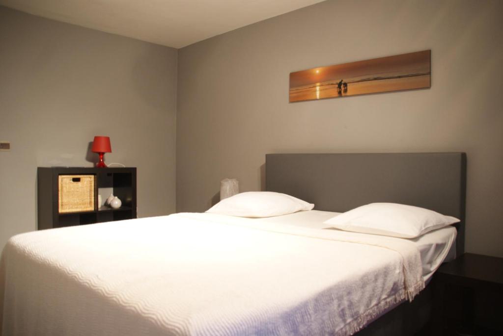 a bedroom with a large bed with white sheets at Vakantie Logies Allo Allo in Poperinge