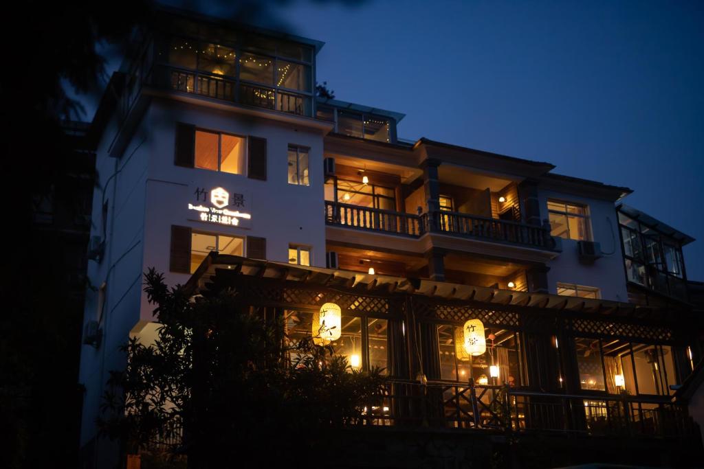 een hoog wit gebouw met 's nachts verlichting bij Moganshan Bamboo View Guesthouse in Deqing
