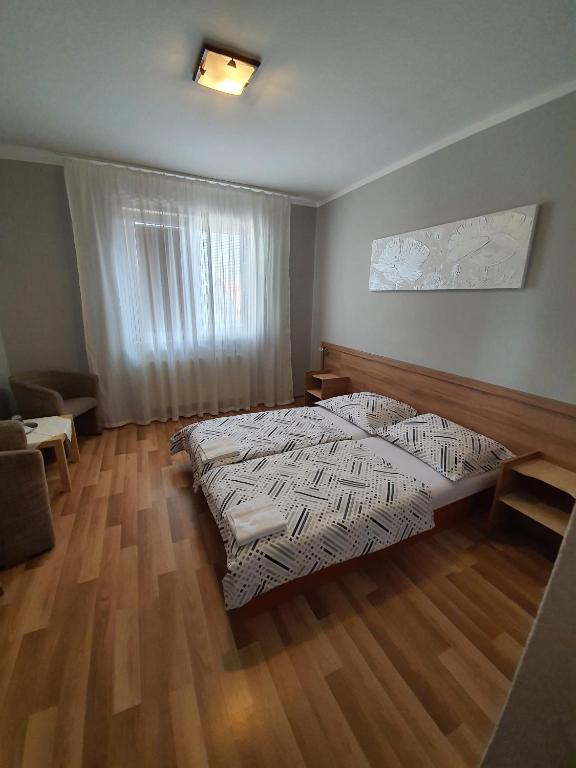1 dormitorio con 1 cama y suelo de madera en Penzion M.L.K, en Hlohovec