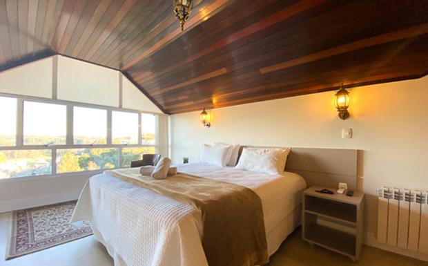 a bedroom with a large bed and a large window at Letto Hotel Flores da Cunha in Flores da Cunha