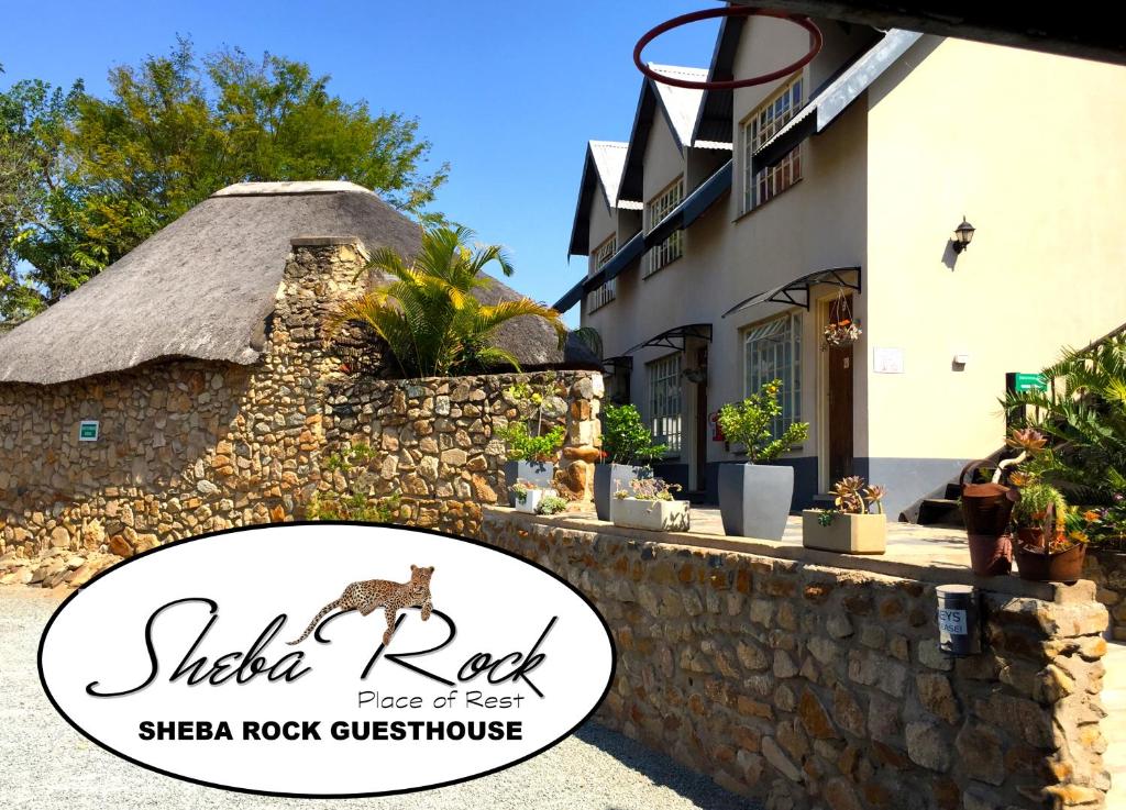 a sign for a sheep rock guesthouse next to a stone wall at Sheba Rock Guesthouse in Nelspruit