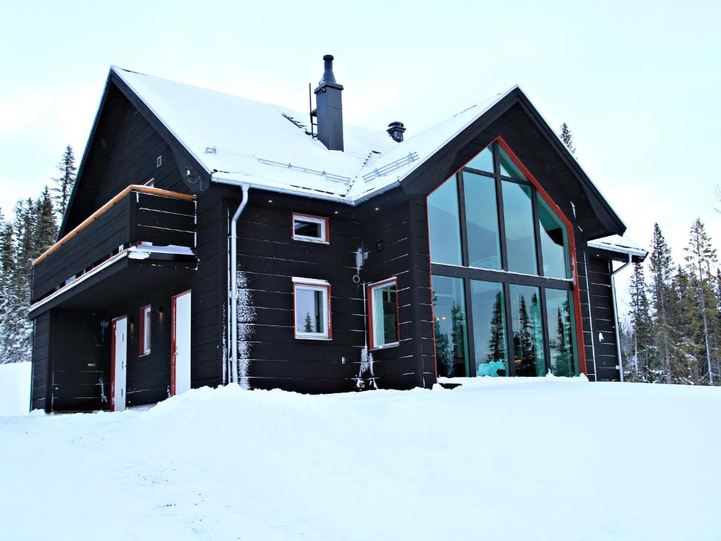 a black house in the snow with trees at Ottsjö Bear Lodge in Ottsjö