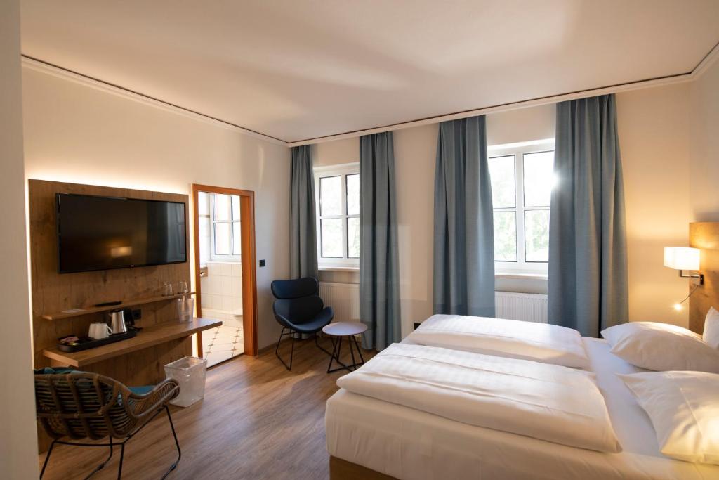 a hotel room with a bed and a flat screen tv at Landhotel Kauzenberg in Bad Kreuznach