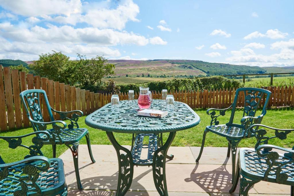 a table with four chairs and a pink bottle on it at Finest Retreats - Quail's Nest Cottage in Edlingham