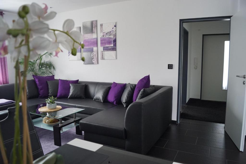 a living room with a couch and purple pillows at La Domus Superior Osnabrück Lotte in Osnabrück