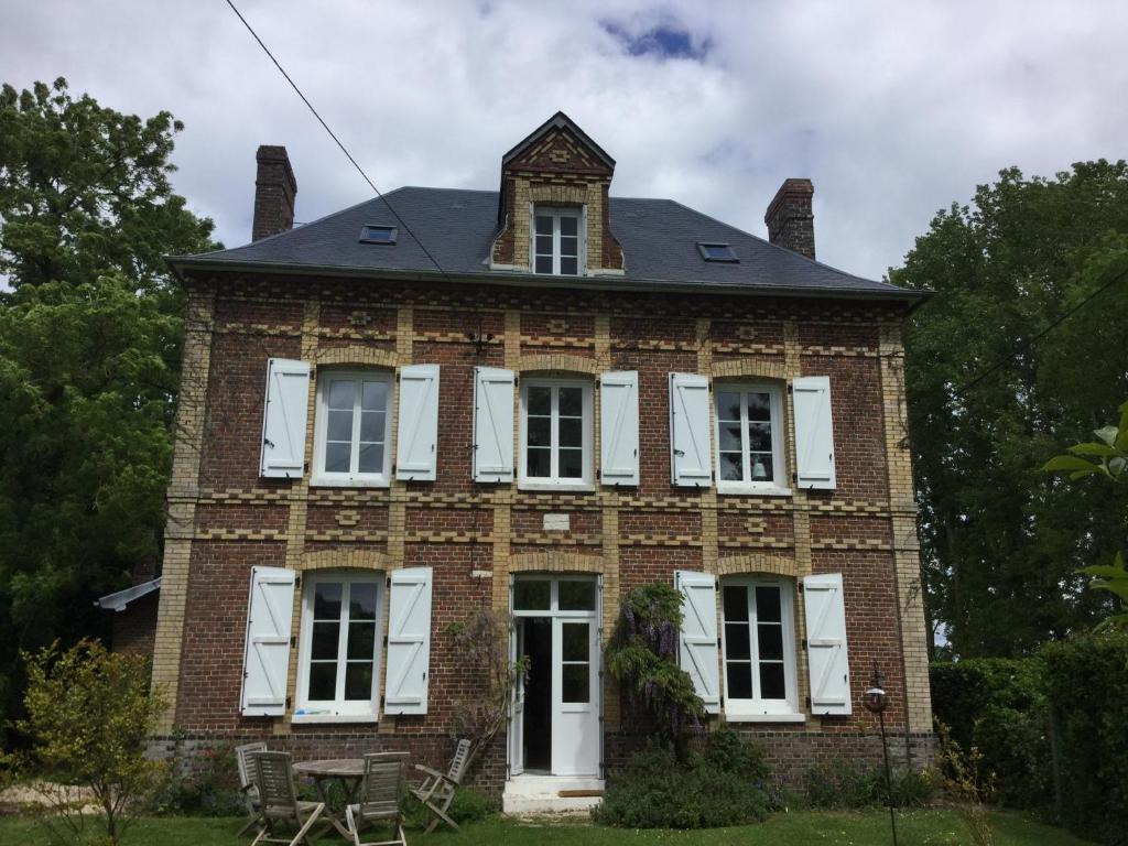 ein altes Backsteinhaus mit weißen Fensterläden in der Unterkunft Numéro 7 in Le Tronquay