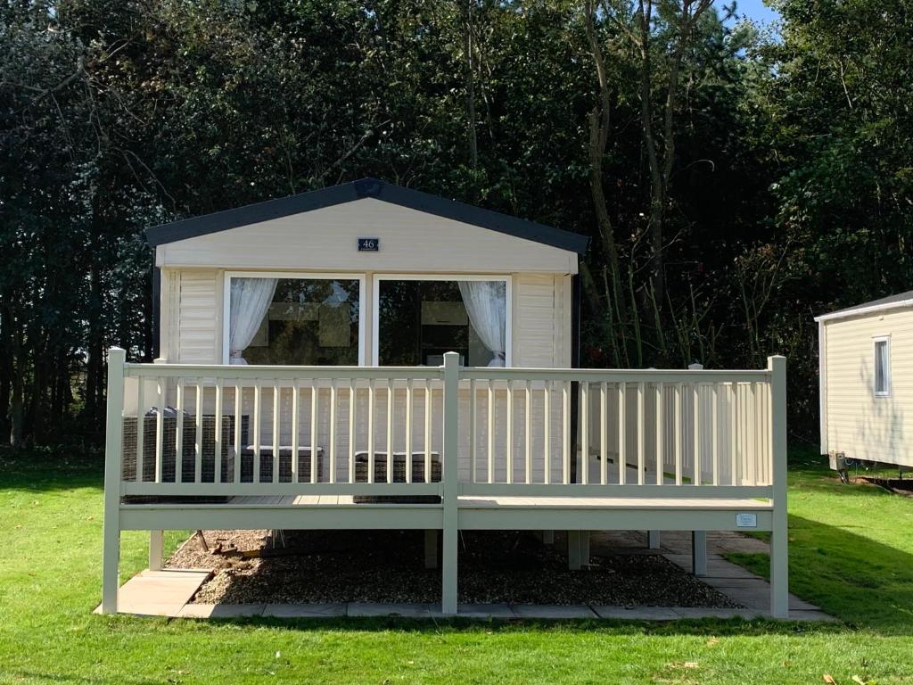 a dog house sitting on a bench in the grass at Modern, Spacious 2 bedroom caravan - Thorpe Park Haven, Cleethorpes in Cleethorpes