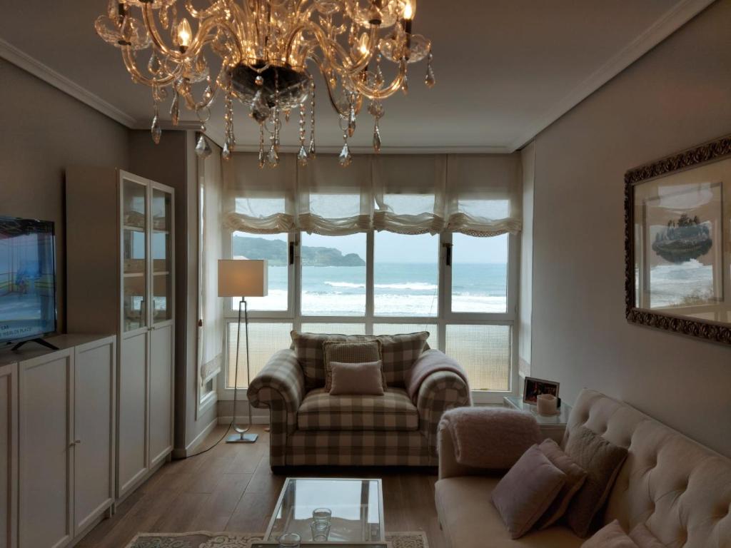 a living room with a couch and a chandelier at Apartamento a pie de la playa Noja in Noja