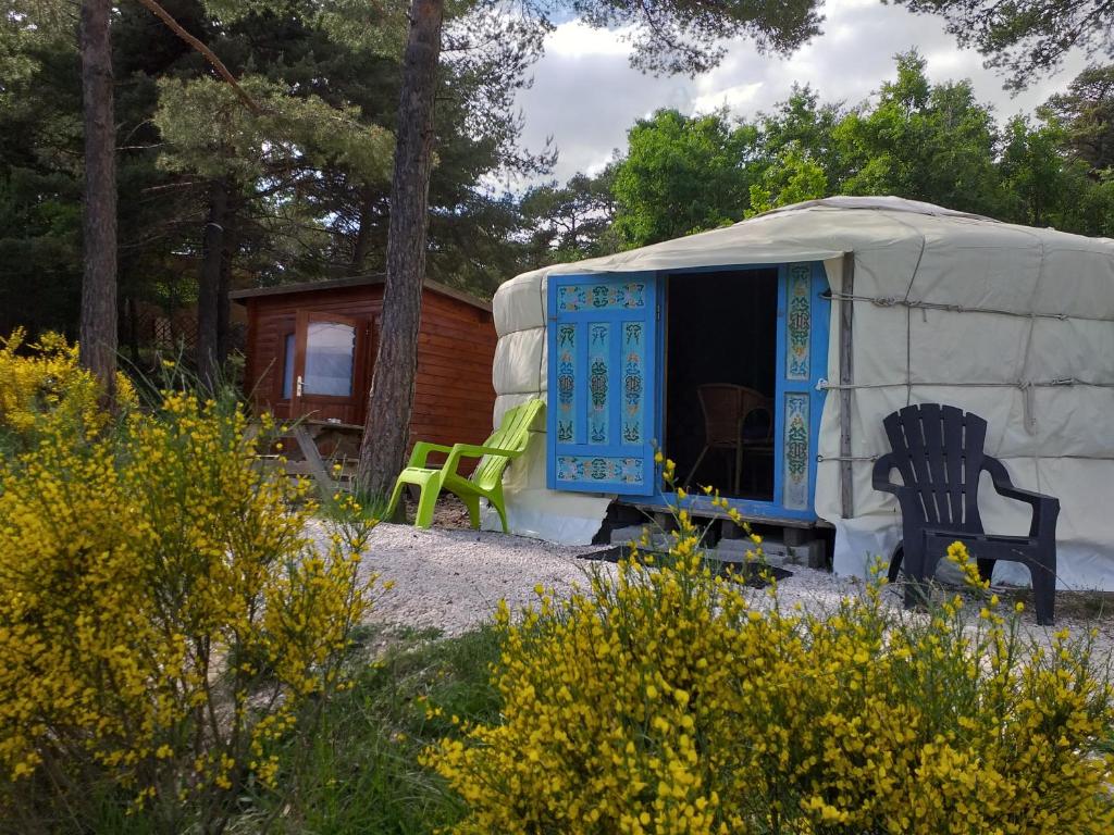 een yurt met een blauwe deur en een groene stoel bij Destination Ailleurs in Castellane