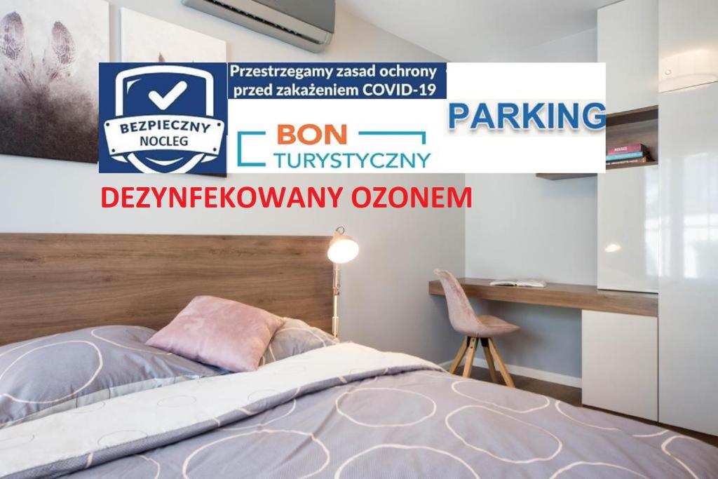 1 dormitorio con cama, escritorio y cartel en Nowoczesne apartamenty w centrum Krakowa, en Cracovia
