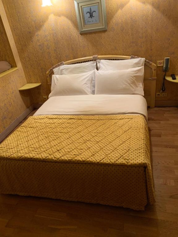 a bedroom with a bed with a yellow comforter at Hotel De La Tour in Pont-de-lʼArche