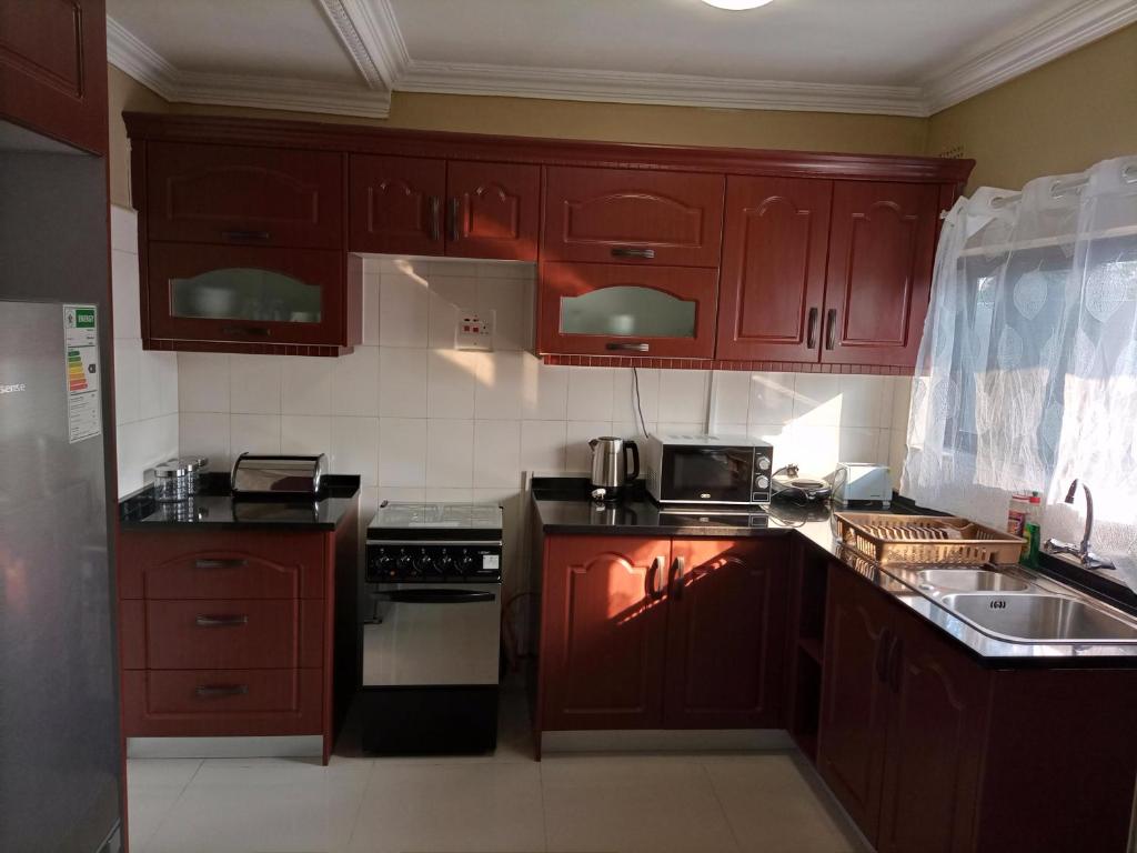 a kitchen with wooden cabinets and a stove top oven at Semuya Apartments in Ndola