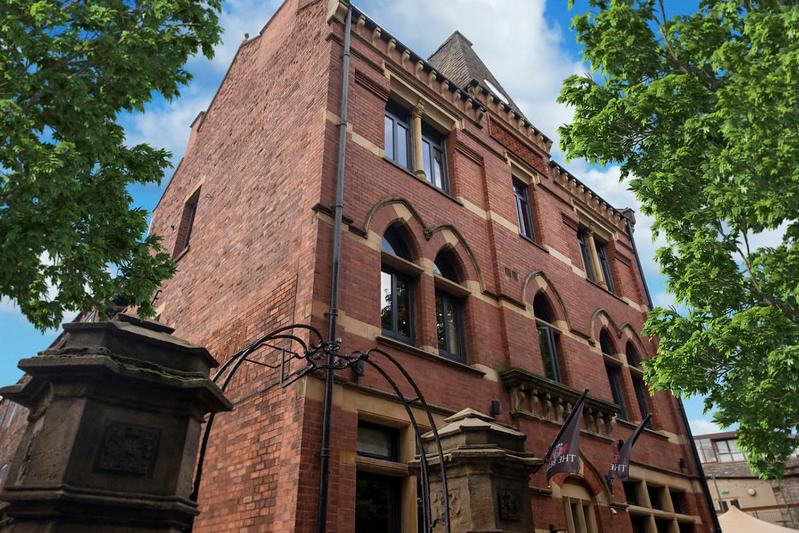 a tall brick building with a clock tower at The Bells - Luxury Serviced Apartments in Leeds