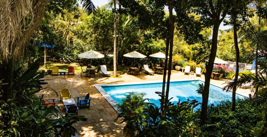 a swimming pool with tables and chairs and umbrellas at Atmosphera Pousada in Arraial d'Ajuda