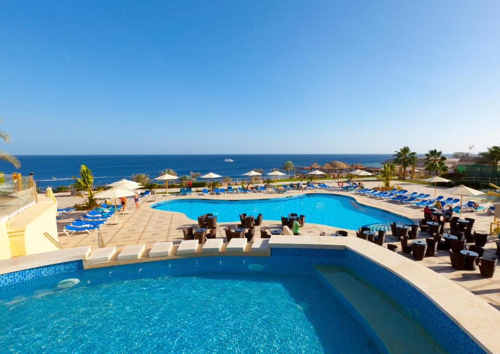 a pool with chairs and the ocean in the background at Island View Resort in Sharm El Sheikh
