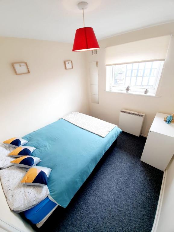 a bedroom with a blue bed with a red lamp at Rayleigh Town Centre 3 Bedroom Apartment in Rayleigh