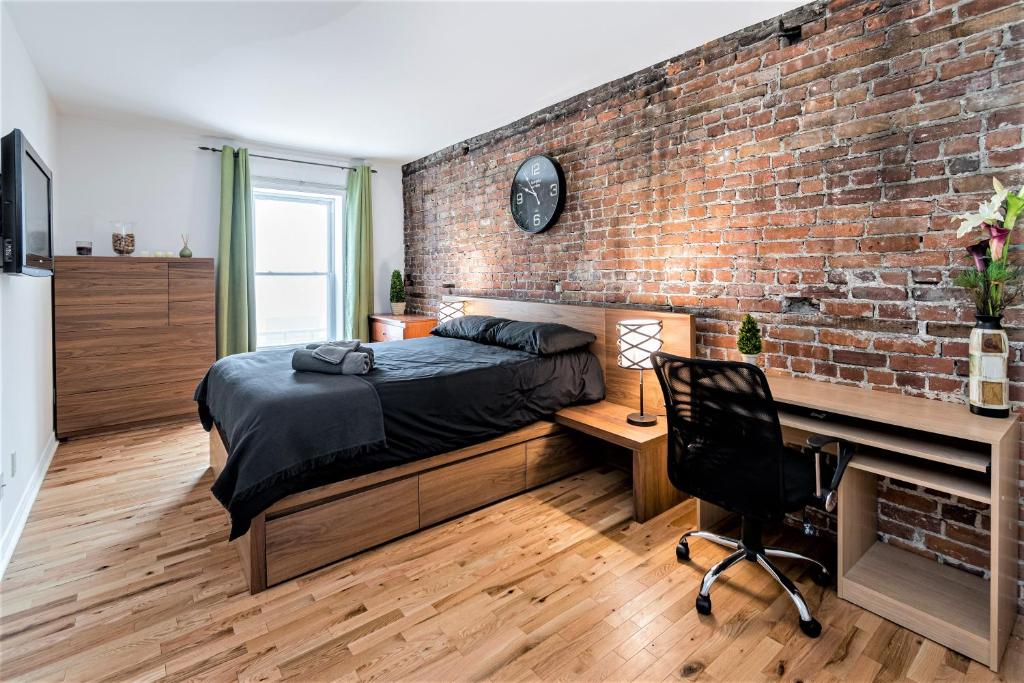 a bedroom with a brick wall and a bed and a desk at Le Théâtral - En plein coeur de l'action avec stationnement in Quebec City