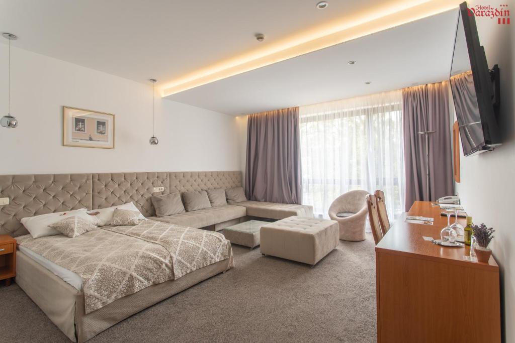 a bedroom with a bed and a couch and a tv at Hotel Varazdin in Varaždin