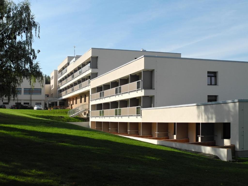 a white building with a grass field in front of it at Hotel VZ Měřín in Merin