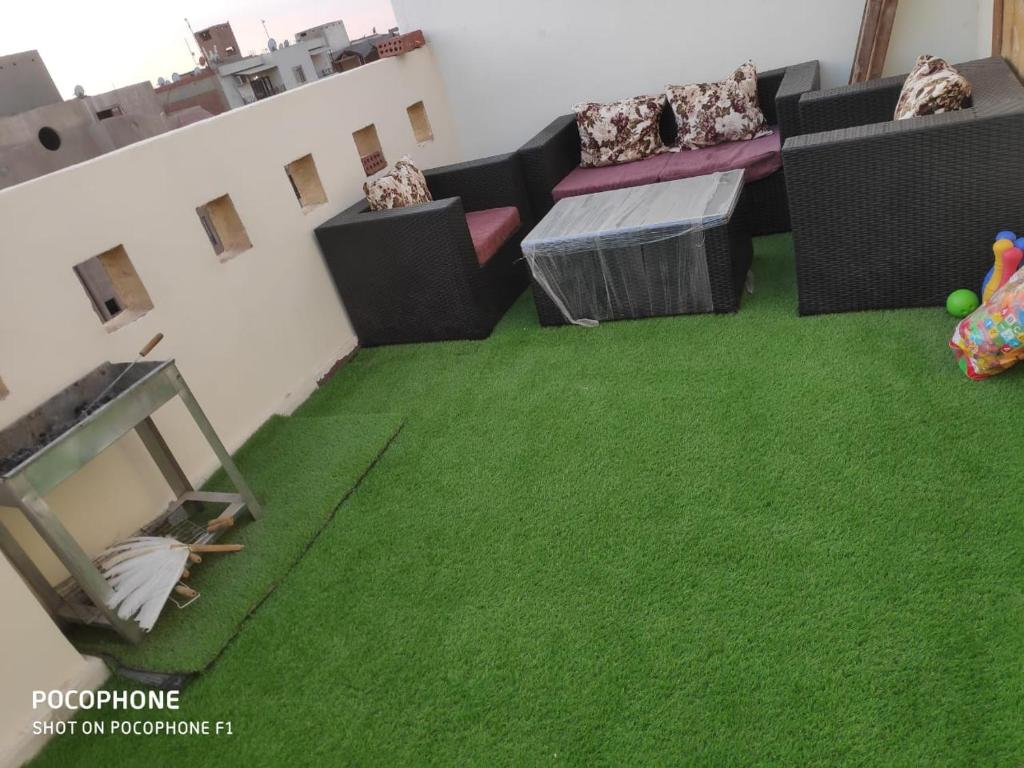 a living room with green carpet and a tv at شقة كلاسيك بمساحة خضراء قريبة من الحصري in 6th Of October