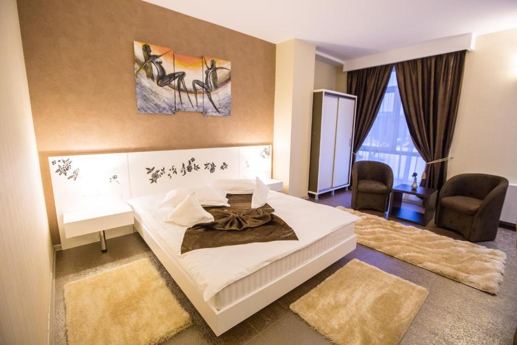 a bedroom with a large white bed and two chairs at Hotel Meliss in Craiova