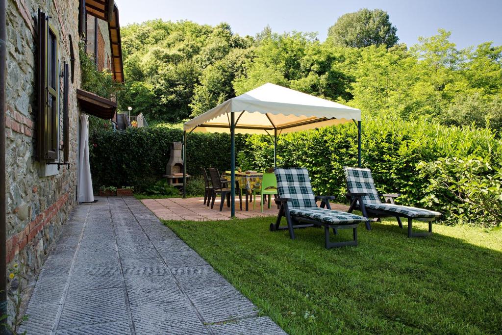 a patio with a table and chairs under an umbrella at 3 bedrooms house with furnished terrace and wifi at Castelnuovo di Garfagnana in Castelnuovo di Garfagnana