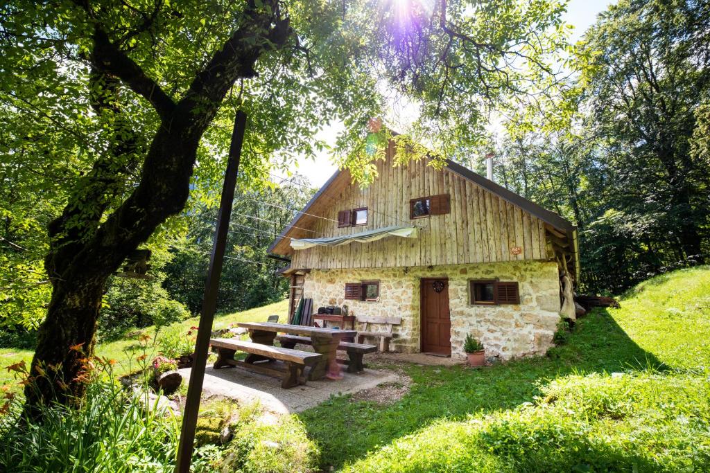 a stone house with a picnic table and a bench at Miha lodge - Mihčevo pleče in Soča