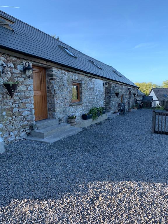 a stone house with a door on a gravel yard at The Reindeer Retreat Daisy Double in Carmarthen