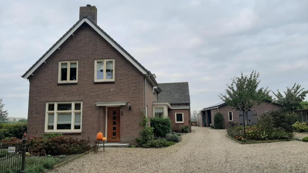 a brick house on a gravel driveway at Bed en Boterham in Hedel