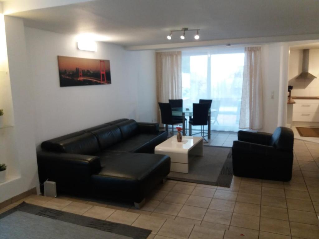 a living room with a black leather couch and a table at Appartement Confidence in Bürstadt