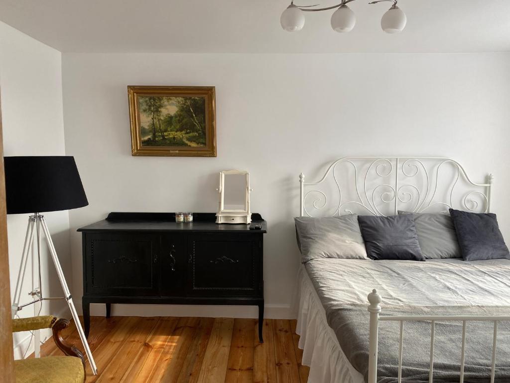 a bedroom with a bed with a black dresser and a lamp at Skrunda Apartments Rustic in Skrunda