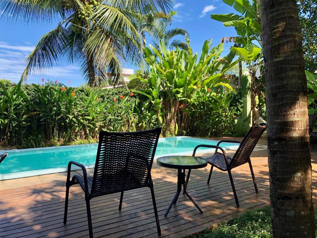 2 sillas y una mesa en una terraza junto a una piscina en Jataí Guest House en Ubatuba
