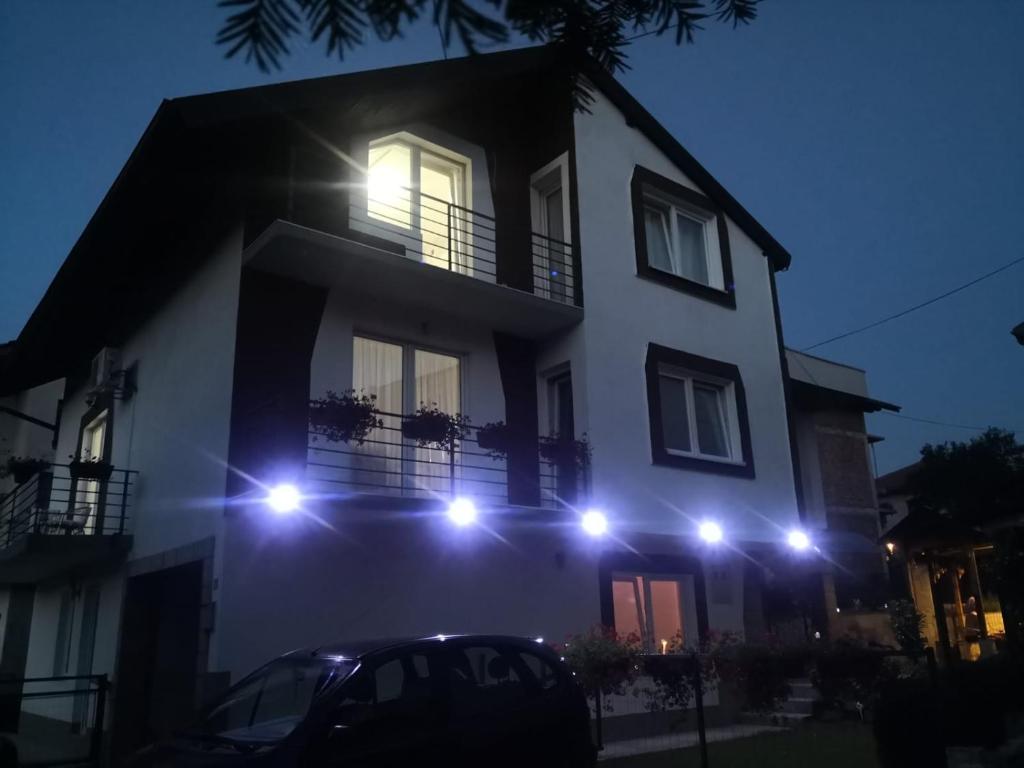 a white house with lights on the side of it at Apartman Volijak in Jajce