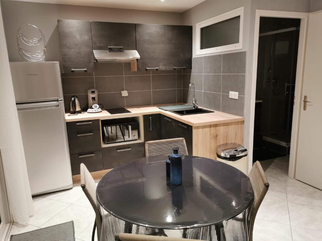 une cuisine avec une table avec des chaises et un réfrigérateur dans l'établissement A l instant présent, à Brison-Saint-Innocent