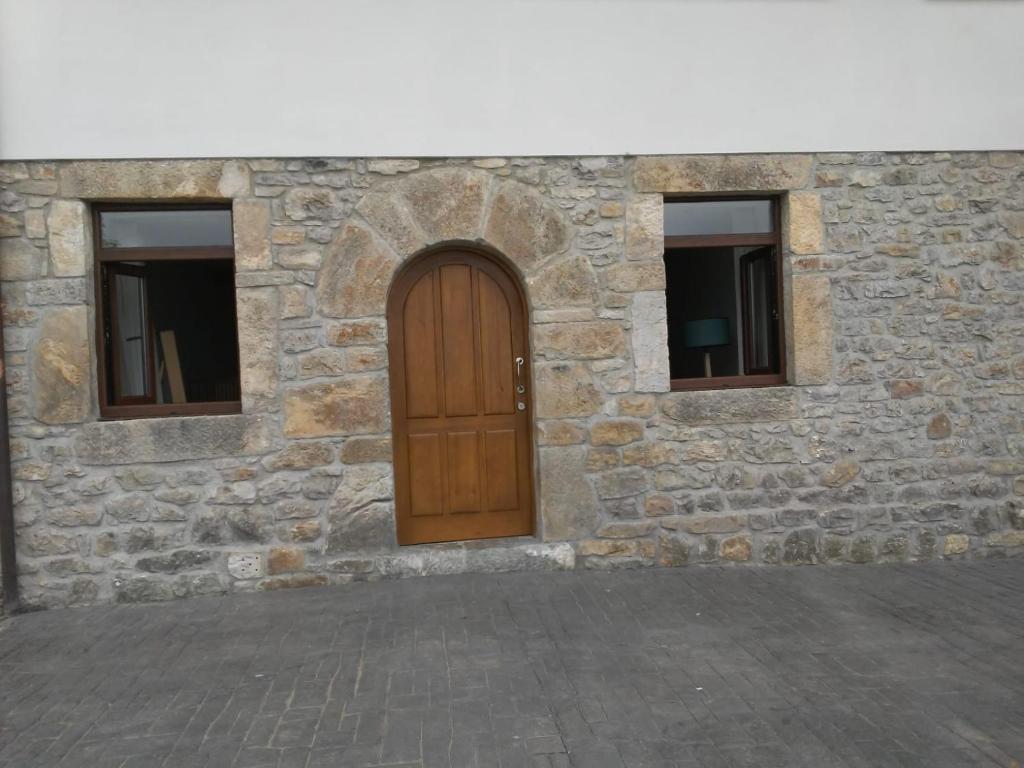 Edificio de piedra con puerta de madera y 2 ventanas en Apartamentos tiu Enrique 1 en Cangas de Onís