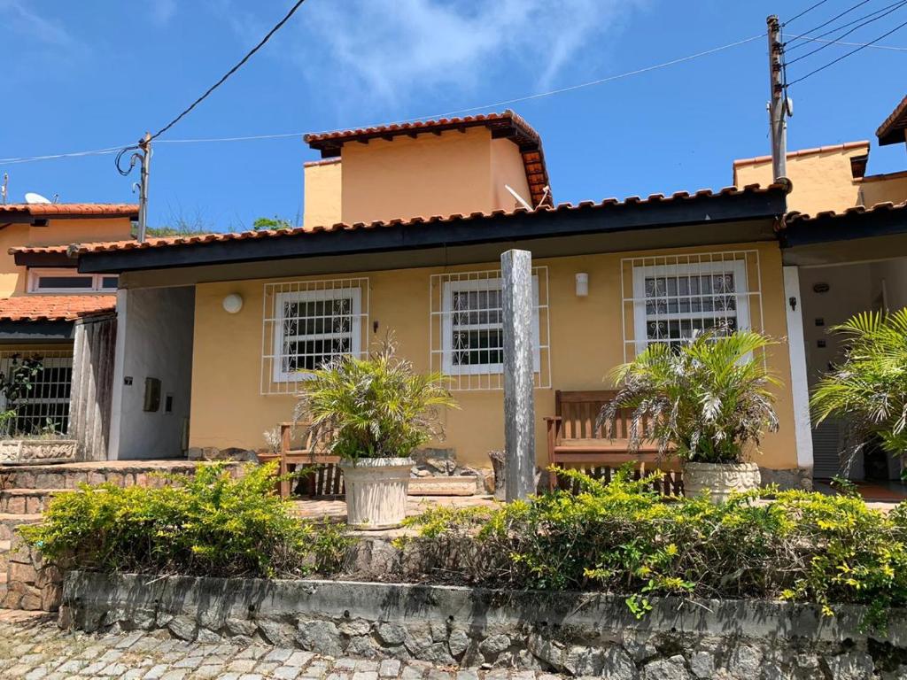 a yellow house with palm trees in front of it at Casa no Parque da Costa do Sol in Arraial do Cabo