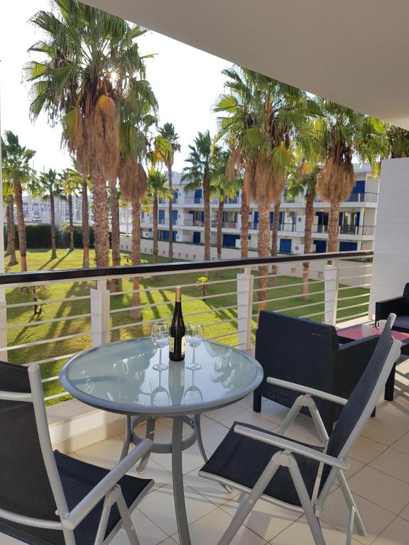 a glass table and chairs on a balcony with palm trees at Lagos Marina Side Apartment in Lagos