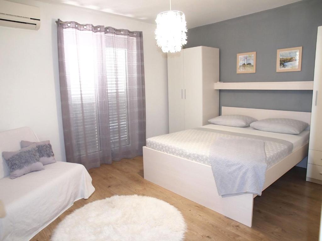 a white bedroom with two beds and a chandelier at Apartmani Igor in Makarska