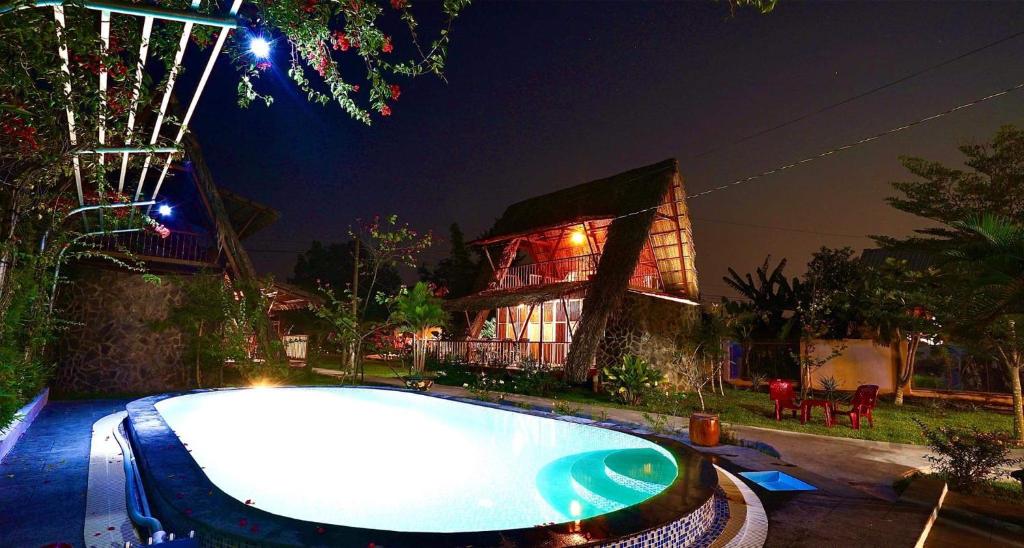 una piscina di fronte a una casa di notte di Mekong Delta Ricefield Lodge a Can Tho